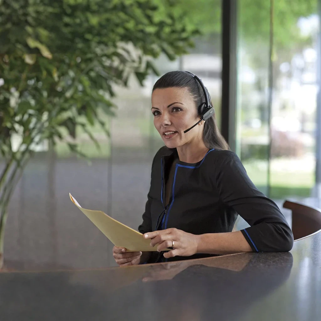 Auriculares Poly CS540/A Reducción de Ruido Monoaural Gancho de Oreja Negro, en uso: mujer en oficina con micrófono boom