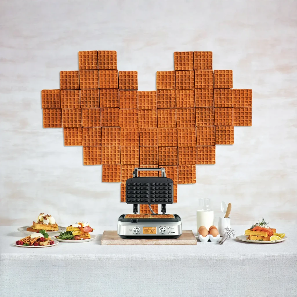 Gofrera Sage The Smart Waffle Pro 1000W Acero Inoxidable SWM620BSS4EEU1, en uso: gofres formando corazón al fondo, plancha