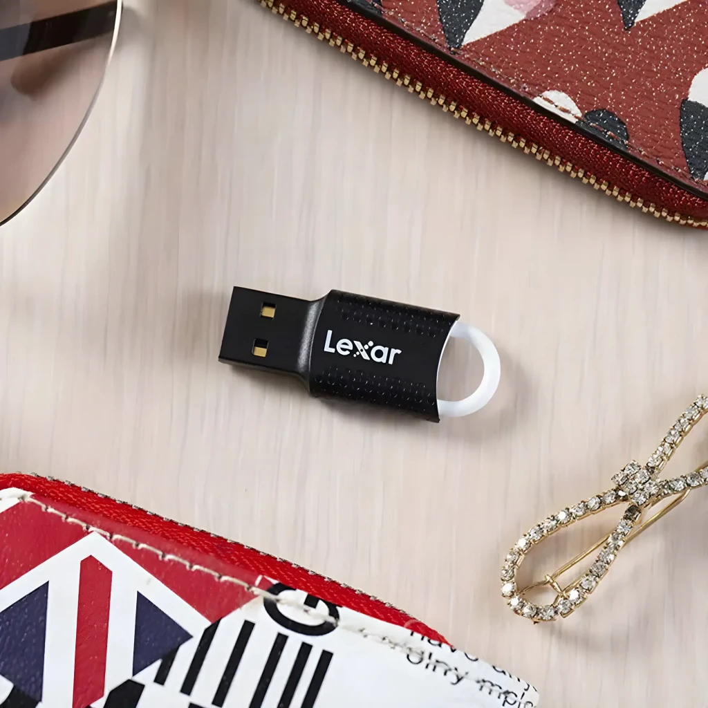 Clé USB Lexar JumpDrive V40 32Go USB 2.0 Noir, en utilisation: sur surface bois avec portefeuille et bijoux, connecteur