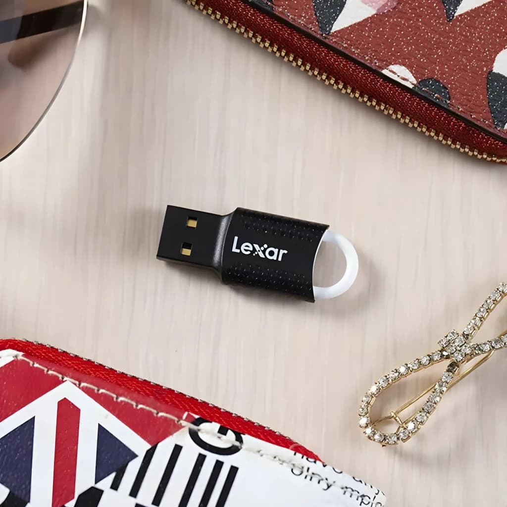 Clé USB Lexar JumpDrive V40 32Go USB 2.0 Noir, en utilisation: sur surface bois avec portefeuille et bijoux, connecteur