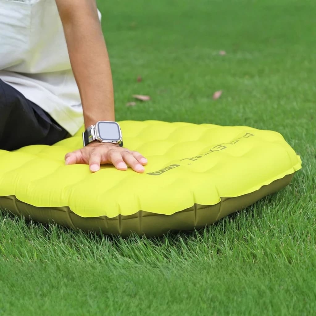Matelas Gonflable Flextail Tiny R09 AVS Momie Vert, en utilisation: main posée sur cellules gonflées dans l'herbe