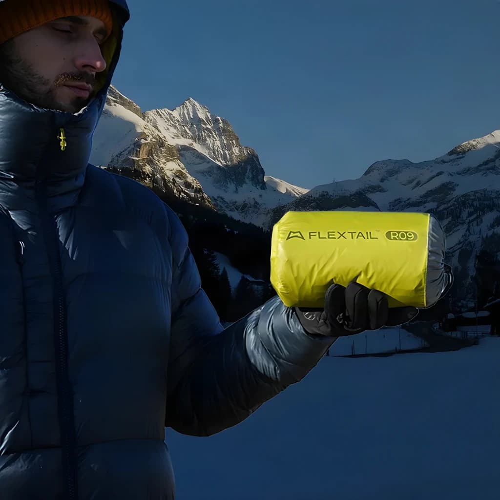 Colchão Insuflável Flextail Tiny R09 AVS Múmia L Verde Valor R 9,4, em uso: alpinista segura o colchão enrolado em montanha