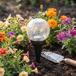 Candeeiro solar Superfire Preto FF16-A, em uso: esfera de vidro craquelado fincada no solo entre flores coloridas