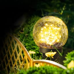 Candeeiro solar Superfire Preto FF16-A, em uso: esfera de vidro craquelado iluminada com luzes quentes entre plantas