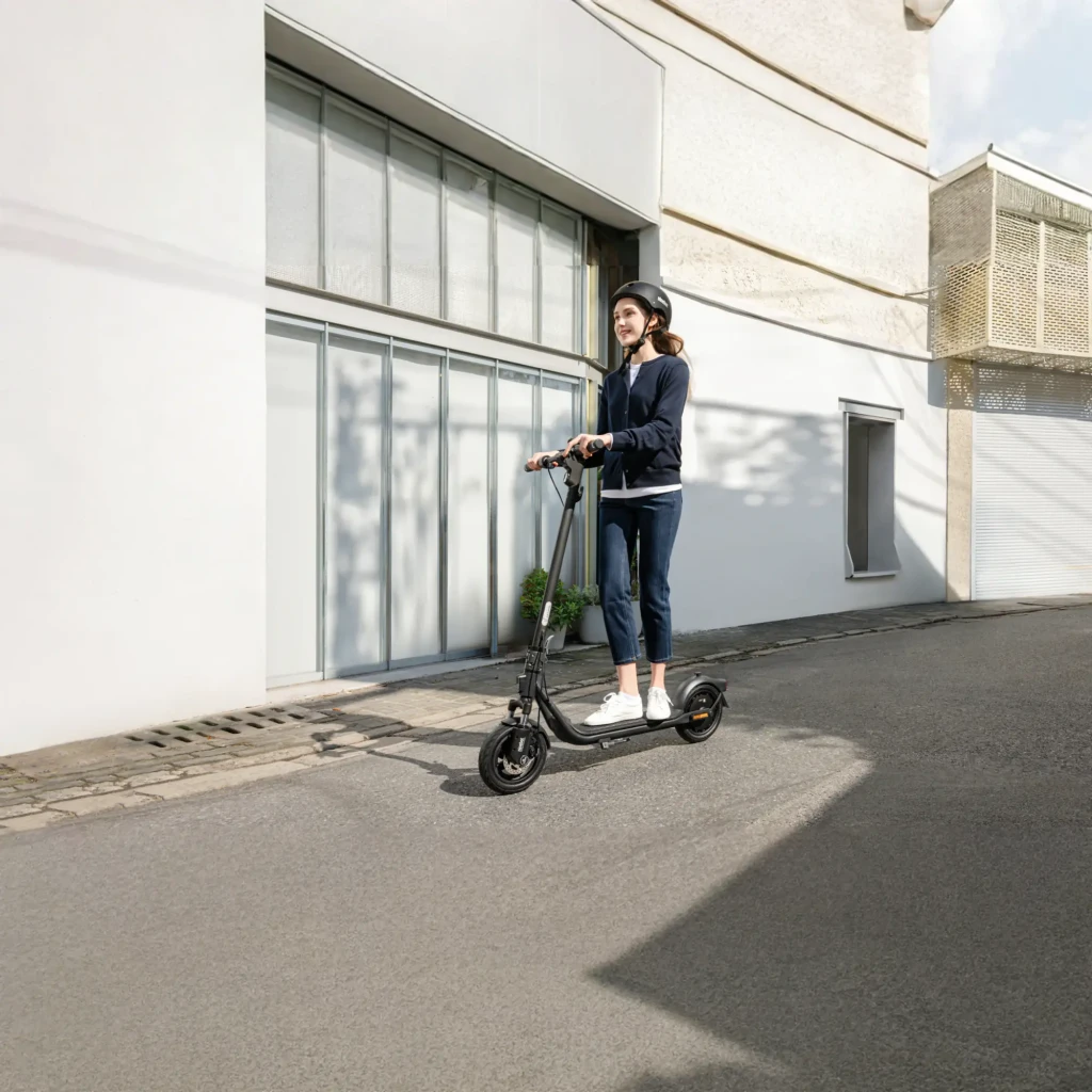 Trotinete Elétrica Ninebot KickScooter F2 D II 400W 55km 20km/h 10 polegadas Vermelho, em uso: mulher com capacete em rua