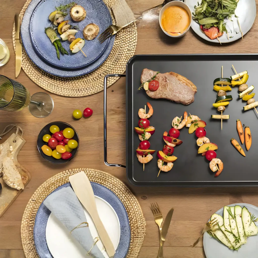 Plancha de asar Princess Table Chef XXL 2500W 600x360mm Negro 102325, en uso: superficie negra con carne, brochetas