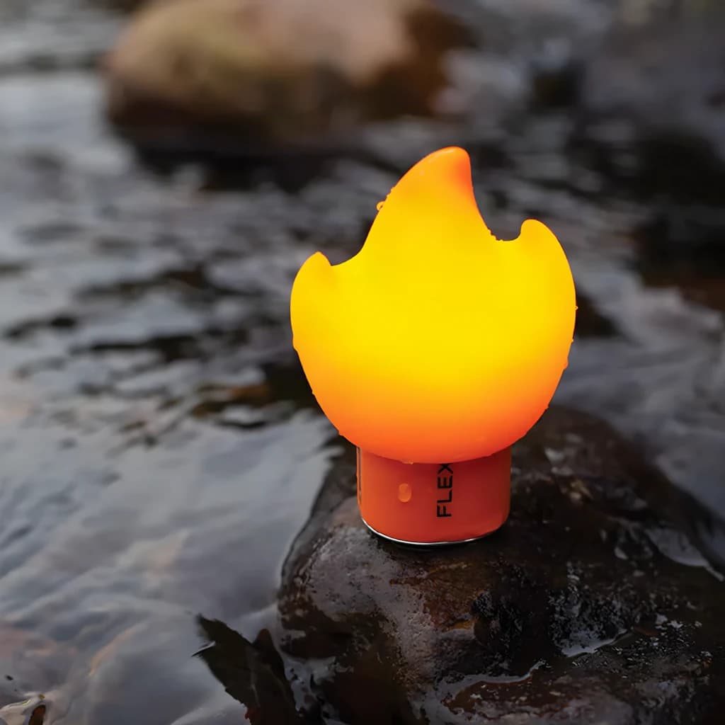 Ecrã difusor Flextail Flame para Tiny Pump 2X Laranja, em uso: difusor iluminado em forma de chama sobre rocha junto