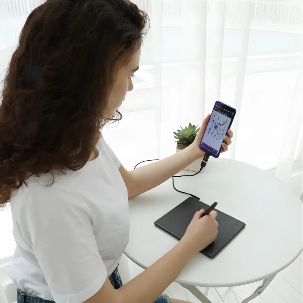 Tableta gráfica Huion HS64 Negro 6,3 pulgadas 5080 LPI 8192 niveles de presión, en uso: mujer dibuja con lápiz conectada