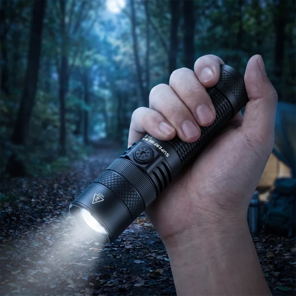 Lanterna LED Superfire F1-S Preto Recarregável 1000 lúmens 275 m, em uso: mão segura a lanterna acesa em floresta noturna