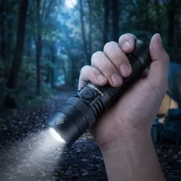 Lanterna LED Superfire F1-S Preto Recarregável 1000 lúmens 275 m, em uso: mão segura a lanterna acesa em floresta noturna
