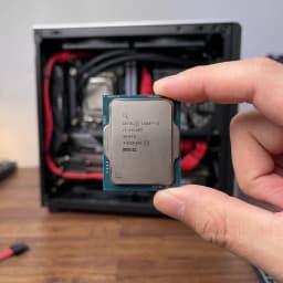 Intel Core i3-14100T 4 Núcleos LGA1700 Tray en uso: mano sostiene el procesador frente a una torre PC abierta con cables