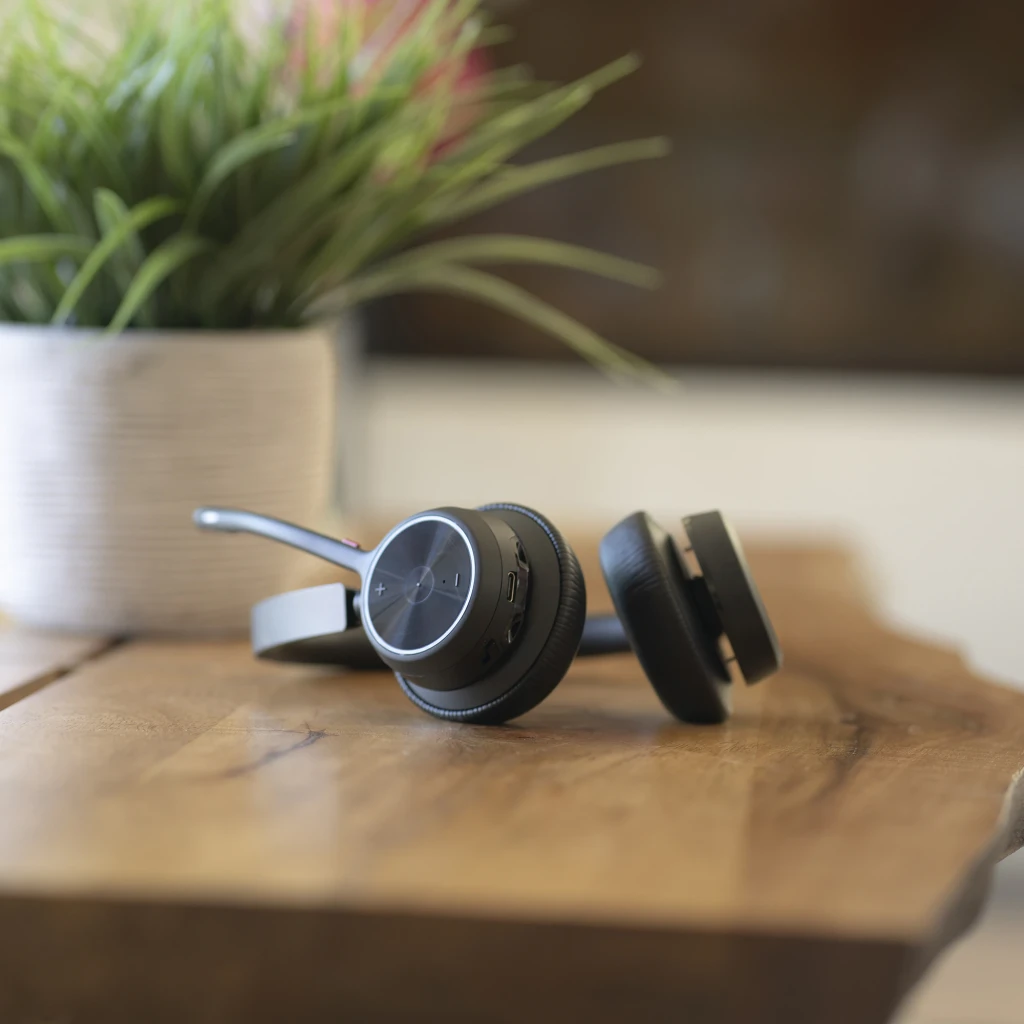 Auriculares Poly Voyager 4320 USB-C Diadema Bluetooth 5.1 47h Negro, en uso: apoyados en mesa de madera con botones y puerto