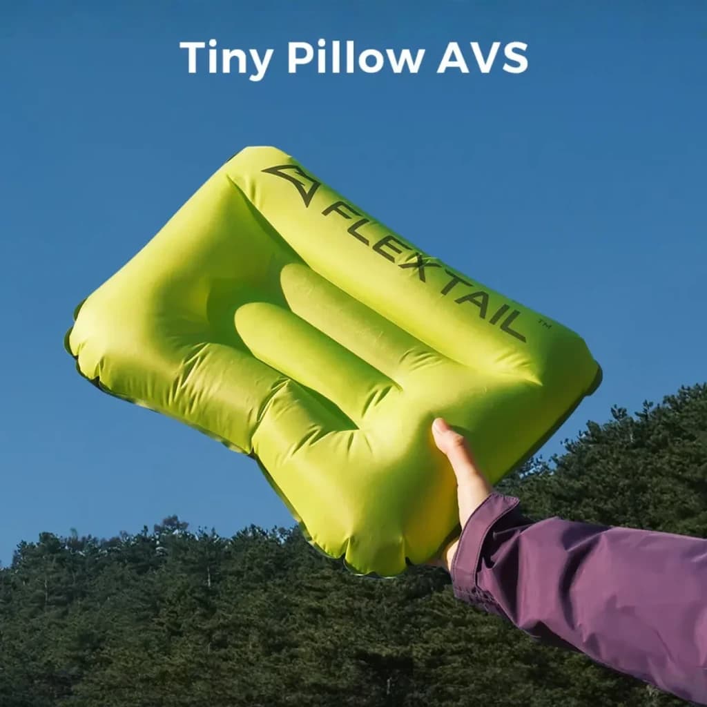 Almofada insuflávelFlextail Tiny Pillow Verde Nylon 20D OEKO-TEX 9,5×6 cm dobrada, em uso: mão segurando insuflada ao ar