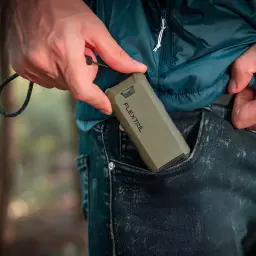 Repelente de mosquitos Flextail Max Repel S Verde, em uso: mão a guardá-lo no bolso de calças de ganga ao ar livre