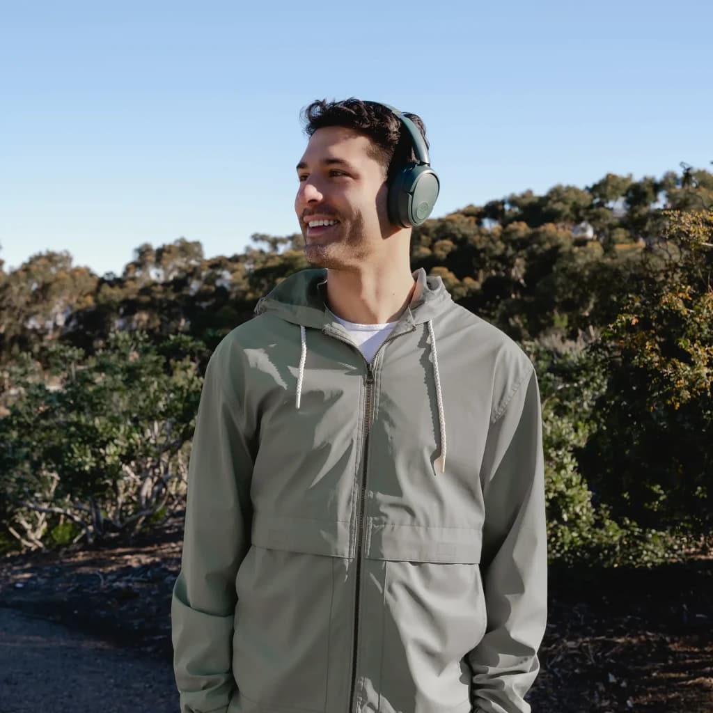 Auriculares JLab Audio Cancelación de Ruido Diadema Bluetooth 5.3 Gris IEUHBJLUXANCRSGE62, en uso: hombre sonriente al aire