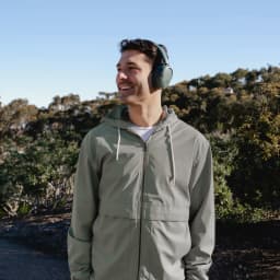 Auriculares JLab Audio Cancelación de Ruido Diadema Bluetooth 5.3 Gris IEUHBJLUXANCRSGE62, en uso: hombre sonriente al aire