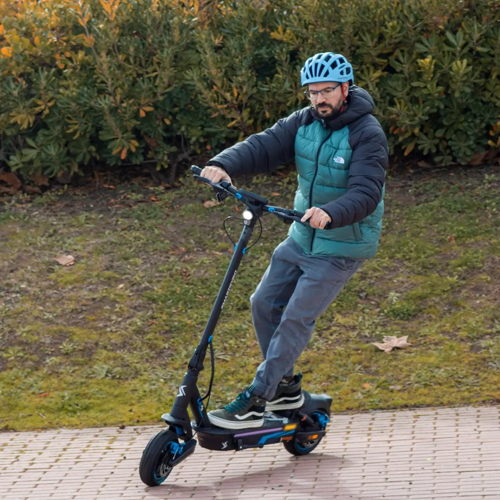 Patinete Eléctrico smartGyro K5 Pro 900W 60km 25km/h 10 pulgadas, en uso: hombre con casco circulando en exterior
