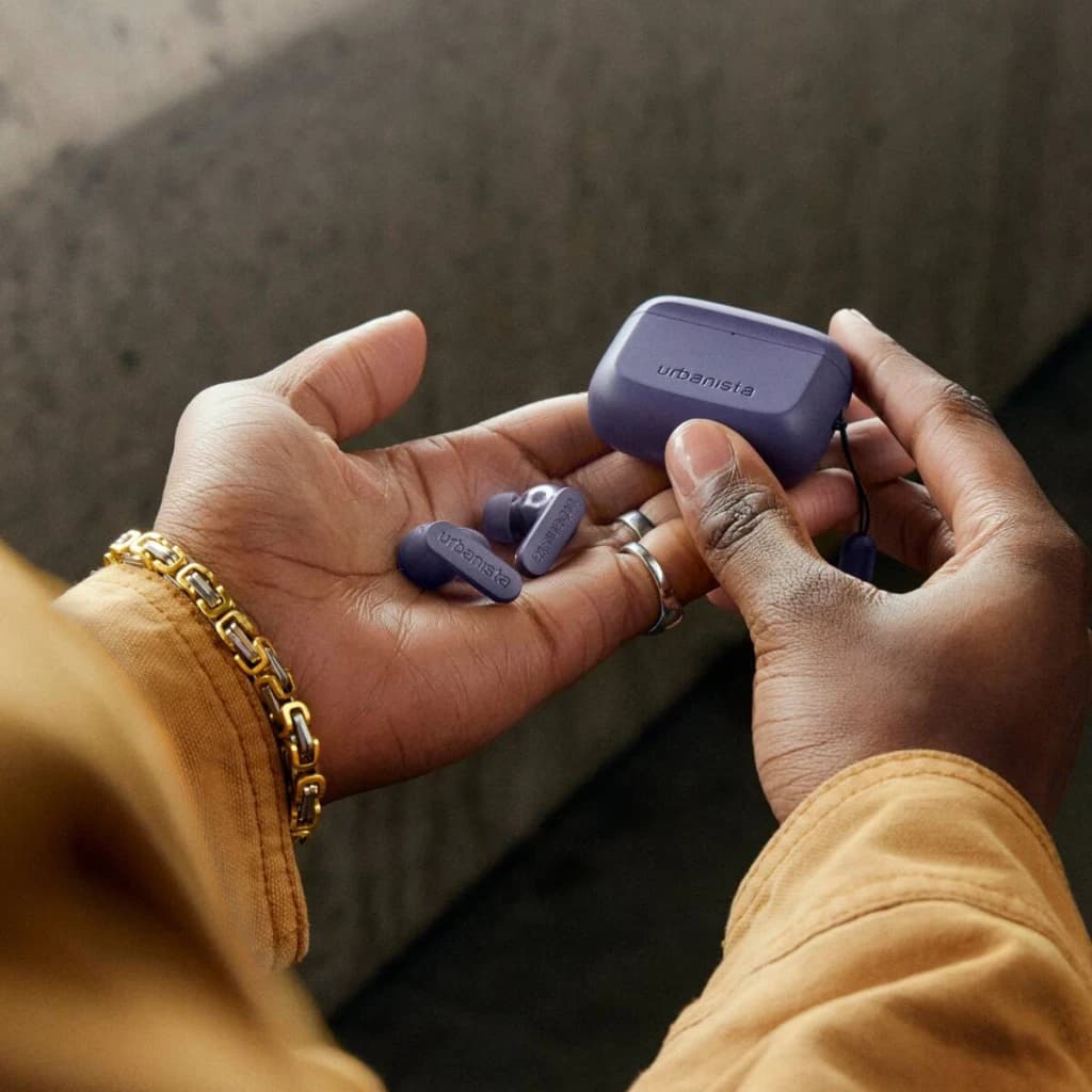 Auriculares Urbanista Palo Alto True Wireless Cancelación de Ruido TWS Violeta, en uso: manos sosteniendo los earbuds