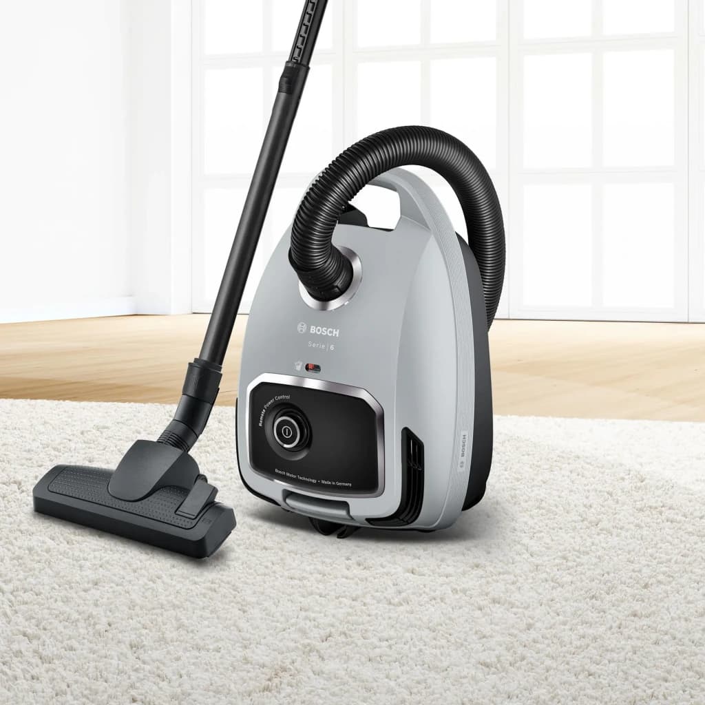 Aspirateur traîneau Bosch Série 6 Noir/Gris 600W BGB6X330, vue latérale: sur tapis blanc avec tube et brosse sol déployés