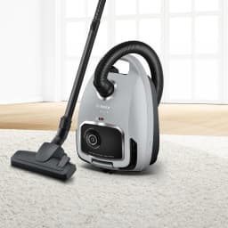 Aspirateur traîneau Bosch Série 6 Noir/Gris 600W BGB6X330, vue latérale: sur tapis blanc avec tube et brosse sol déployés