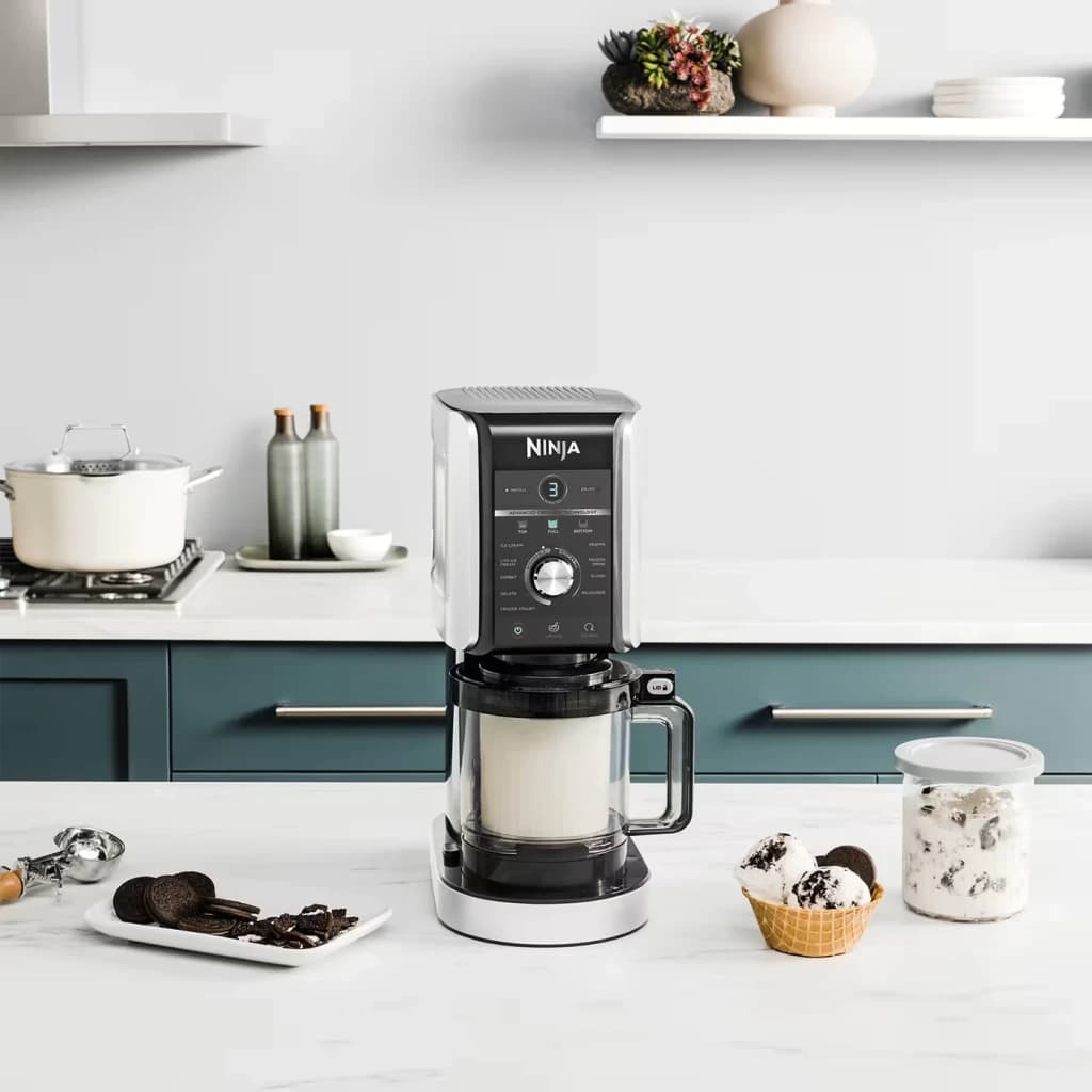 Heladora Ninja CREAMi Deluxe 0,709L 800W Negro NC502EU, en uso: sobre encimera con mezcla en el bol, helado de galleta