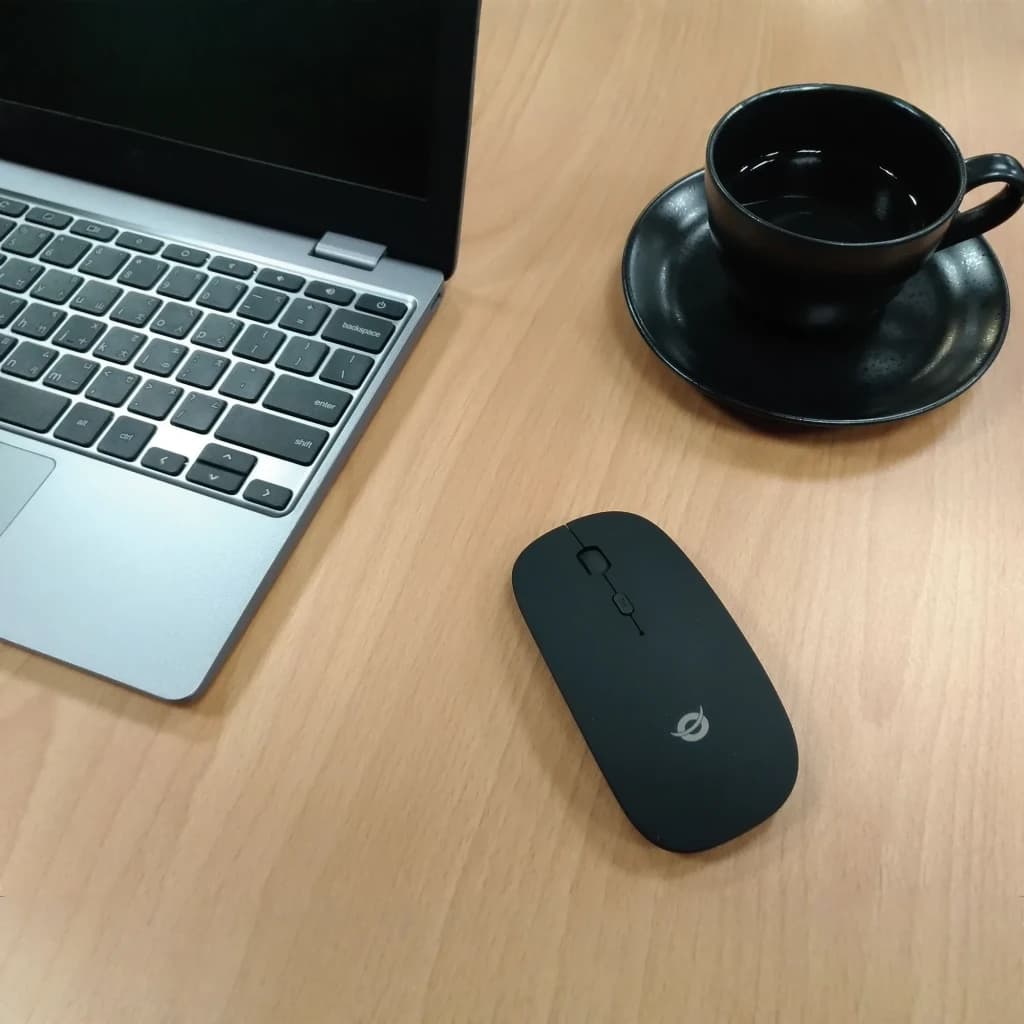 Ratón Conceptronic Negro Bluetooth LORCAN01B, en uso: sobre escritorio de madera junto a portátil plateado y taza negra