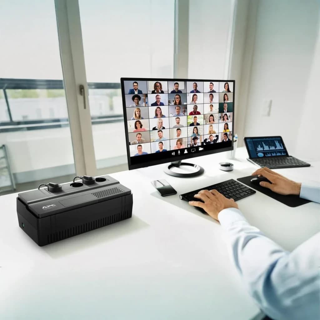 SAI APC Easy UPS Línea Interactiva 1000VA 600W Negro BV1000I-GR, en uso: sobre escritorio junto a monitor con videollamada