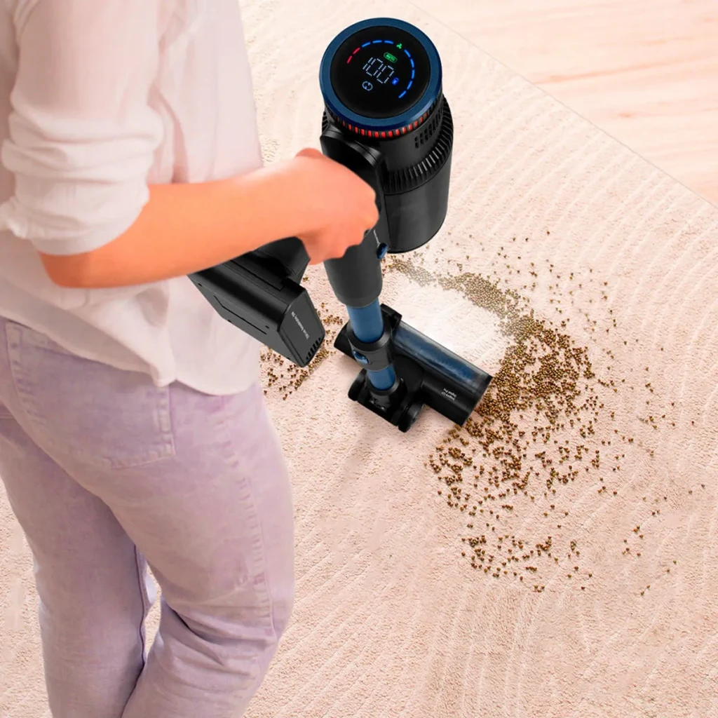 Aspirateur balai Ufesa Inspire U7 Digital PRO Noir/Bleu Sans fil 26000Pa 500W 80min, en usage: femme aspire des débris