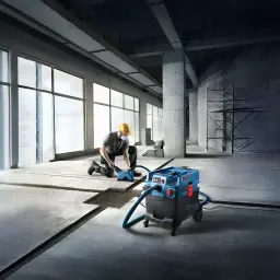 Aspirateur industriel sec/humide Bosch GAS 400 A Professional Bleu Sans Fil 1200W, en utilisation: ouvrier ponçant sol béton