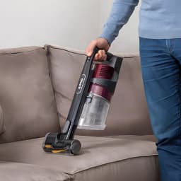 Aspiradora escoba Shark IZ251 2 en 1 Burdeos Sin Cable 45V 80min, uso en sofá: modo portátil limpiando tapizado gris