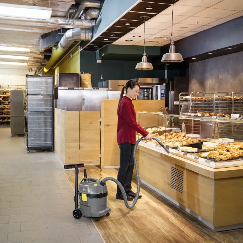 Aspiradora Industrial Kärcher NT 22/1 Ap L 25,5 kPa 1300W, en uso: mujer aspirando mostrador de panadería con manguera