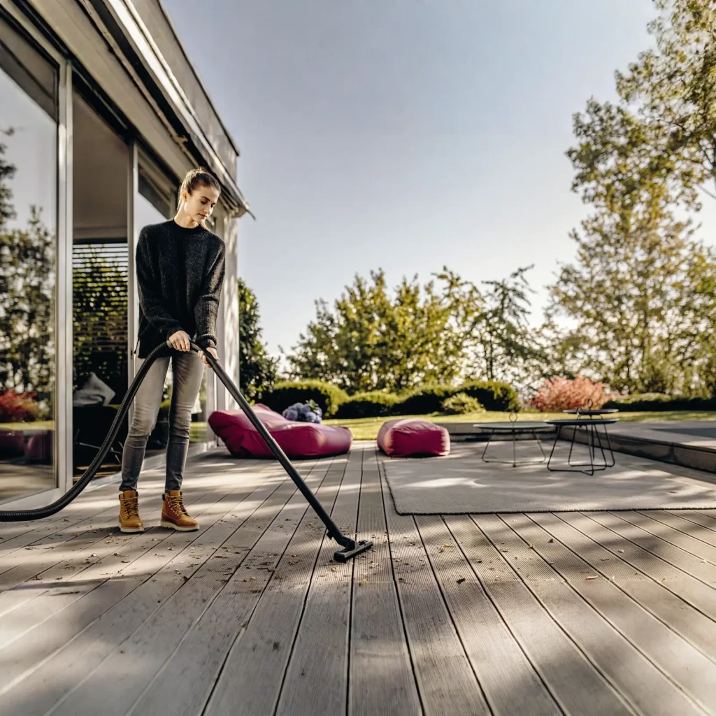Aspiradora en Seco y Húmedo Kärcher WD 4 Amarillo 1000W V-20/5/22, en uso: mujer aspirando hojas en terraza de madera