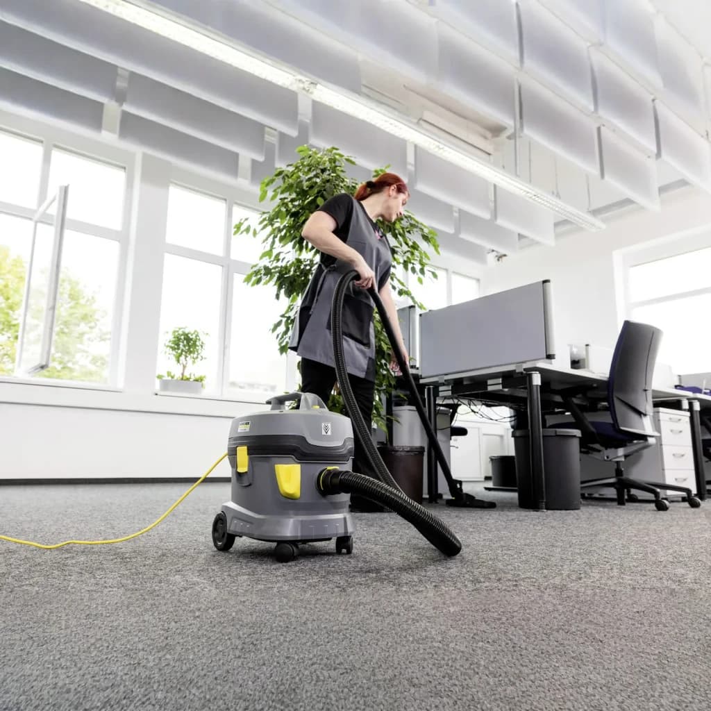 Aspiradora Kärcher T 11/1 Classic HEPA Gris 23,5kPa 850W, en uso: operaria aspira moqueta de oficina con manguera flexible