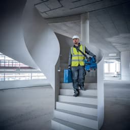 Aspiradora Bosch GAS MC Azul Sin Cable 170mbar 18V-12, en uso: operario con casco baja escalera de obra portando