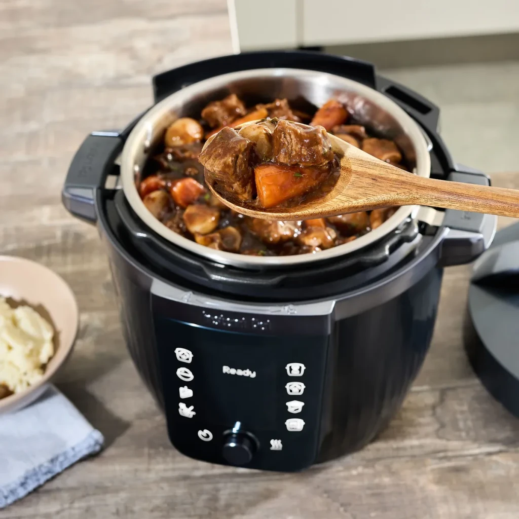 Multicuiseur Instant Pot 5,7L 1200W Noir 920621, en utilisation: cuillère en bois servant un ragoût aux légumes, panneau
