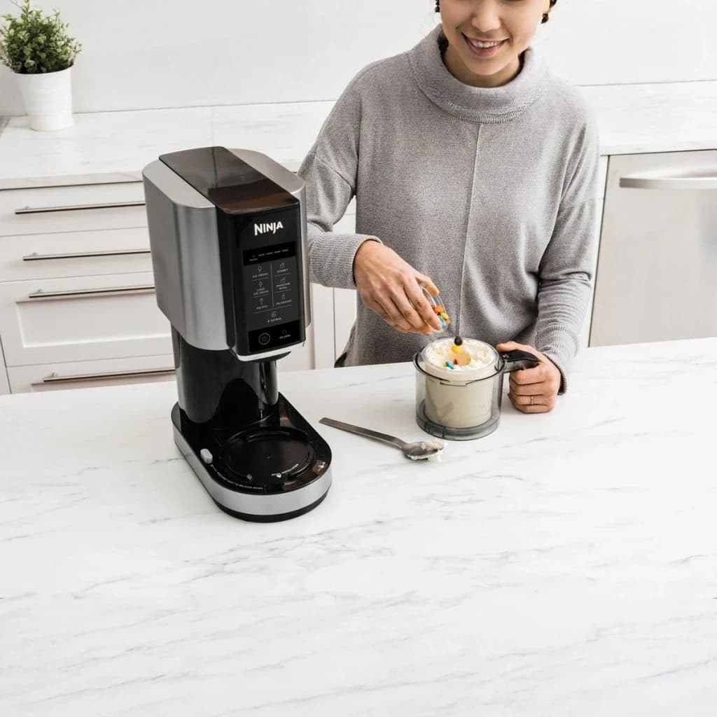 Sorbetière Ninja CREAMi 1,4L 800W Noir/Argent NC300EU, utilisation: personne ajoutant des toppings à la glace dans le bol