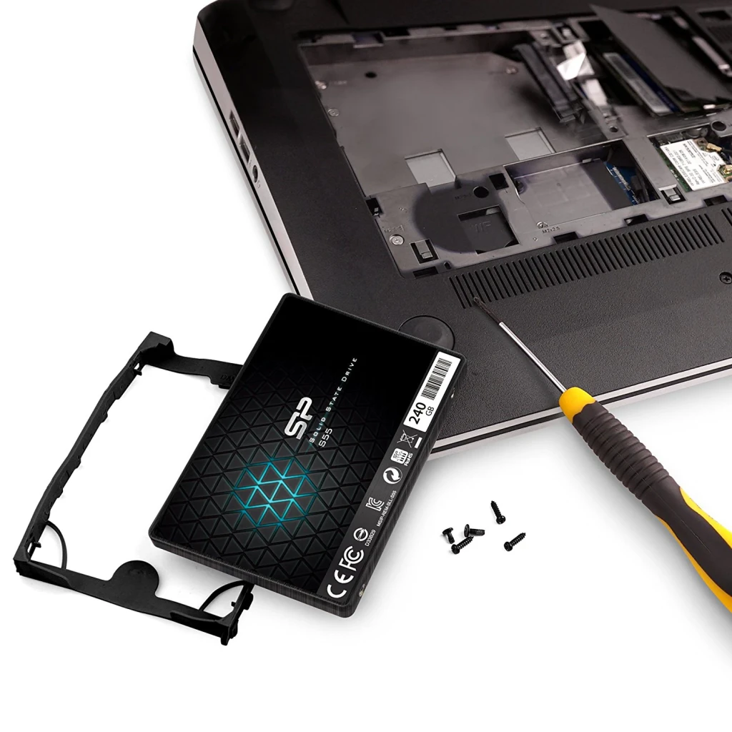 SSD Silicon Power Slim S55 240 Go 2.5 pouces SATA Noir, installation: unité avec support près d'un laptop ouvert et tournevis