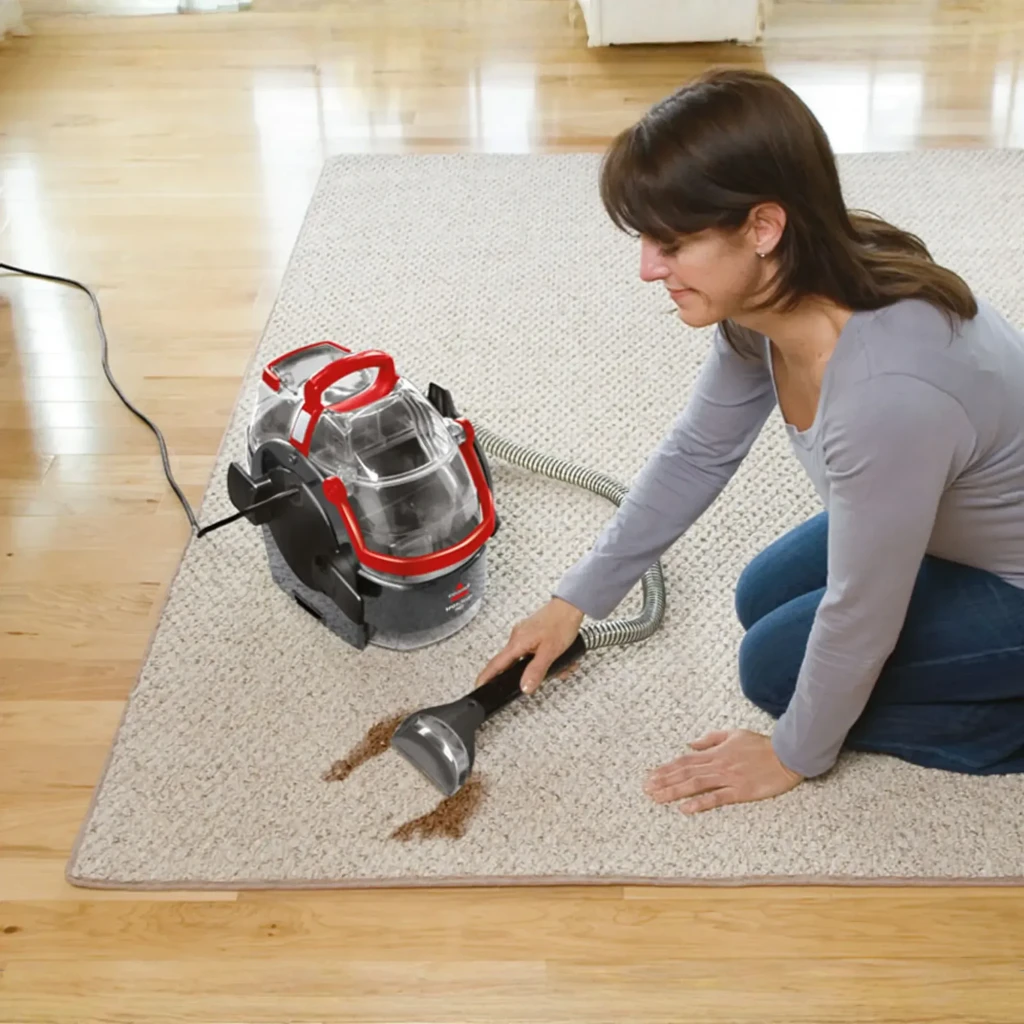 Nettoyeur de taches BISSELL SpotClean Pro 1558N 750W câble 6,7m, en action: femme nettoyant une tache sur tapis avec la buse