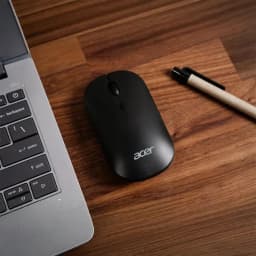 Souris Acer AMR130 Noir Sans Fil Dual Mode, vue dessus: sur bureau en bois à côté d'un laptop et d'un stylo