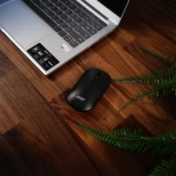 Souris Acer AMR130 Noir Sans Fil Dual Mode, vue de dessus: sur bureau en bois avec laptop Acer et plante verte