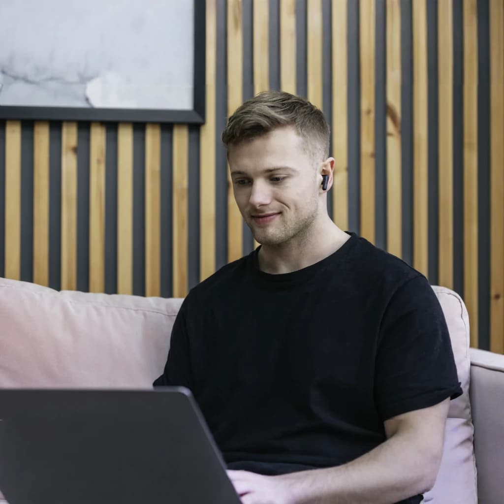 Écouteurs JVC HA-A3T True Wireless TWS Bluetooth 5.1 22h Noir, en utilisation: homme sur canapé avec laptop portant