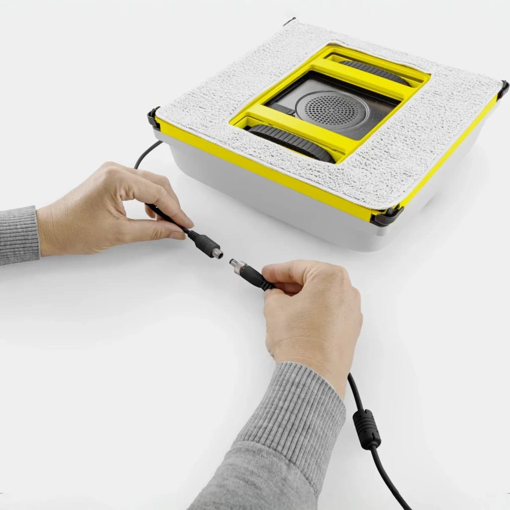 Robot limpiacristales Kärcher RCW 4 Extra 5000Pa 77dB, en uso: manos conectando el cable de alimentación al robot visto