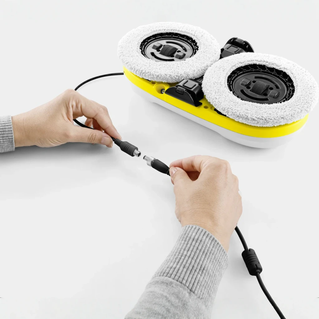 Robot limpiacristales Kärcher RCW 2 Blanco Depósito 70ml Batería, en uso: manos conectando cable de carga al robot visto