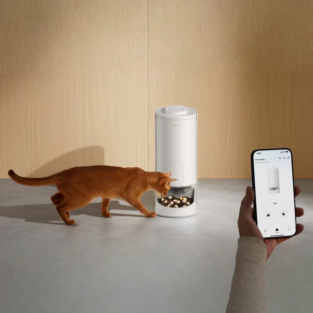 Distributeur automatique MOVA PF10 Pro 3,4L Blanc, en utilisation: chat roux mangeant pendant qu'une main contrôle l'app