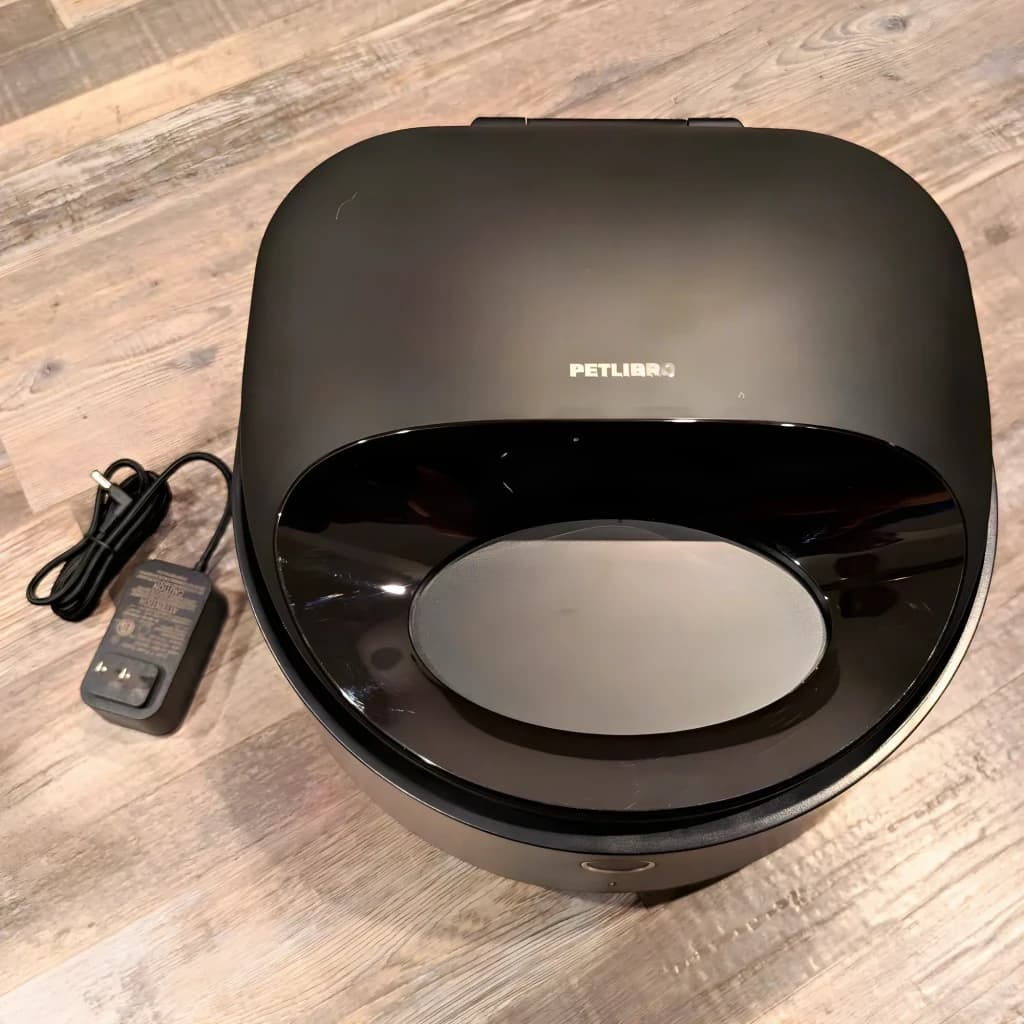 Comedouro Automático Petlibro Polar Smart WiFi App PLAF109 preto, em uso: vista superior sobre chão de madeira com adaptador