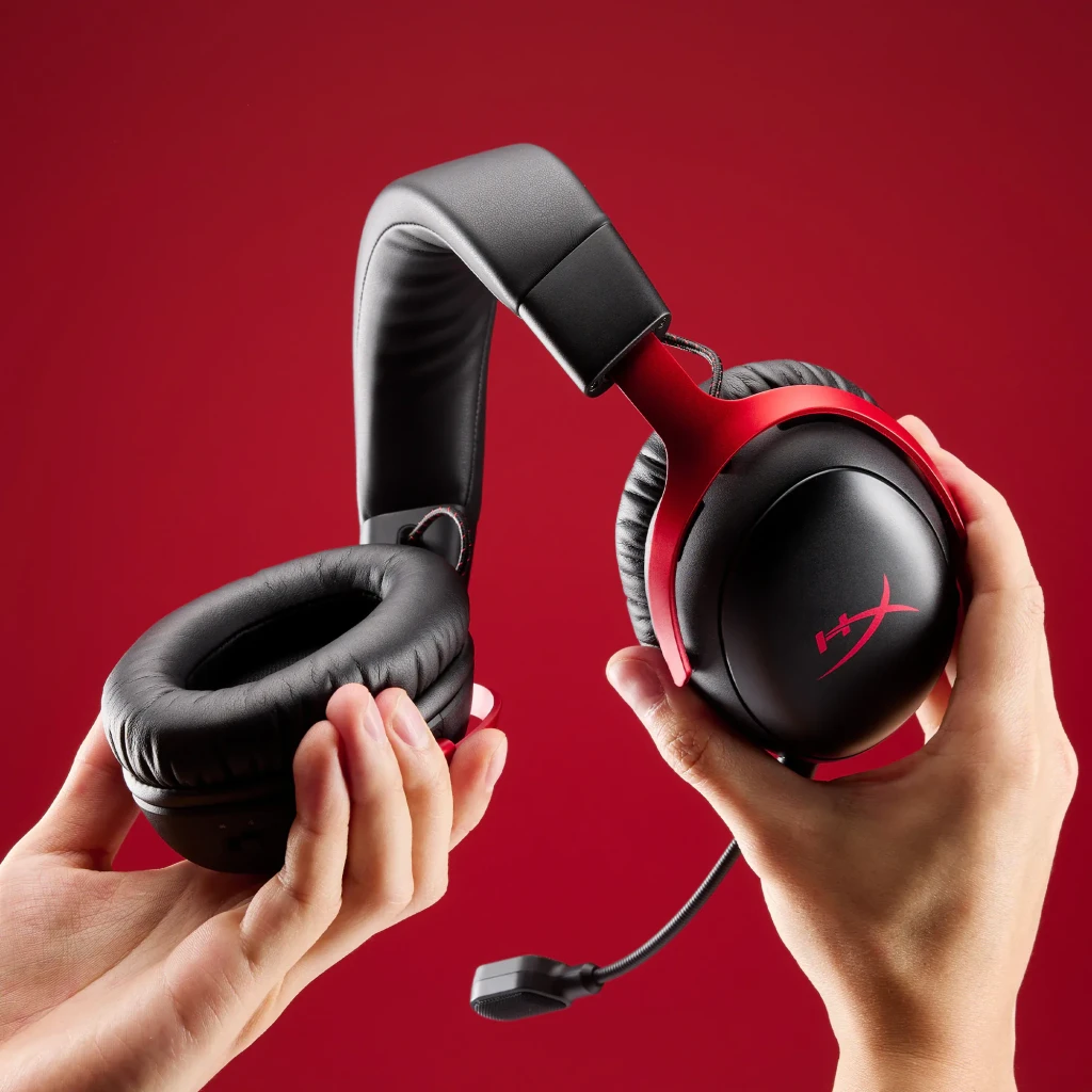 Auriculares Gaming HyperX Cloud III S Wireless Inalámbrico, detalle: dos manos sostienen auricular negro-rojo mostrando
