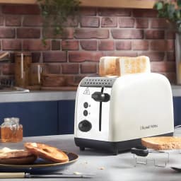 Grille-pain Russell Hobbs Colours Plus 1600W 2 Fentes Crème 26551-56, en utilisation: tranches grillées qui remontent, plan