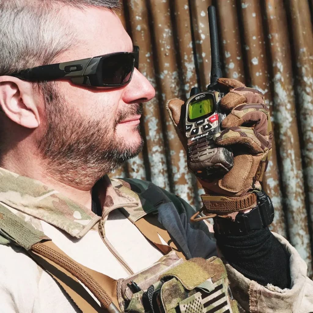 Walkie Talkie Midland G9 Pro PMR 101 Canales Pareja en uso: hombre con equipo táctico sostiene el dispositivo cerca