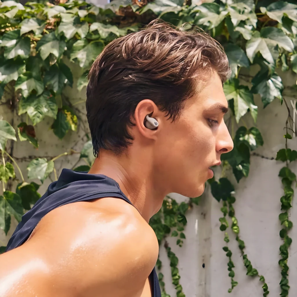 Écouteurs Beats Powerbeats Fit Réduction de Bruit In-Ear Bluetooth, en utilisation: écouteur gris dans l'oreille d'un homme