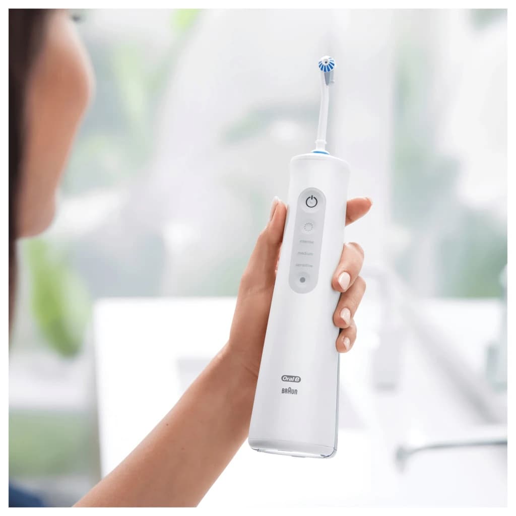 Irrigateur Oral Oral-B AquaCare 6 Pro-Expert Oxyjet Sans Fil Blanc, en utilisation: main tenant l'appareil avec bouton